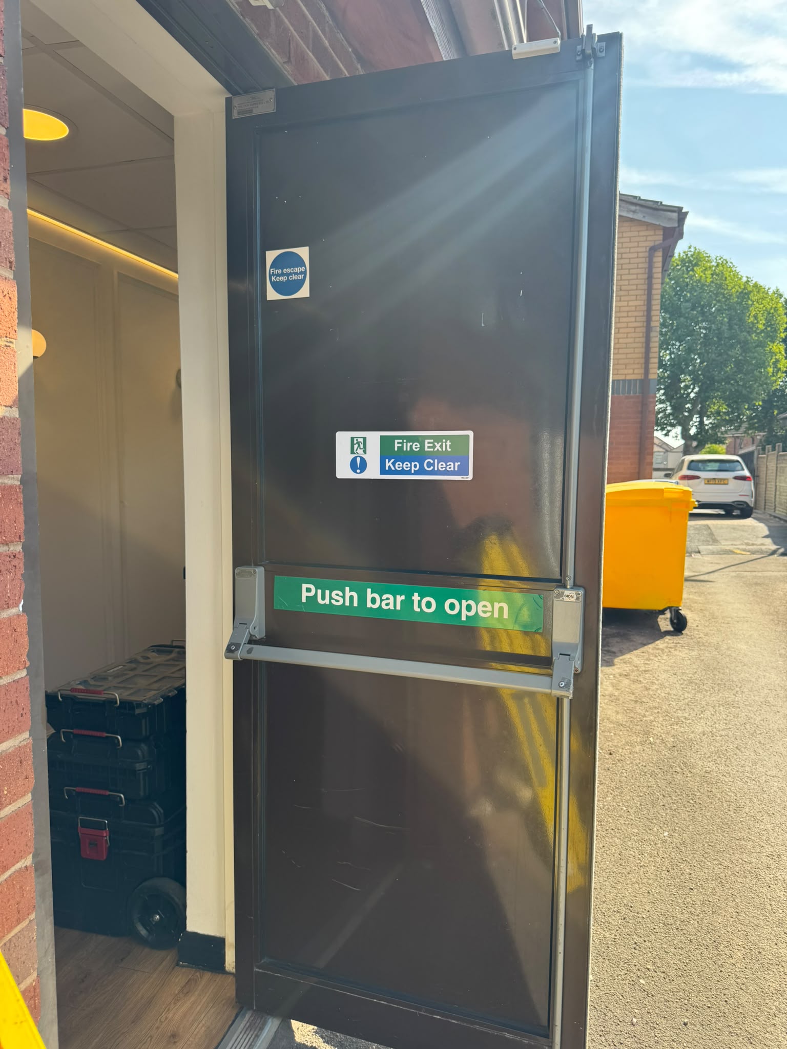 Fire exit door at Holbrooks Dental Coventry propped open, showing the new SION panic bar and push bar to open signage