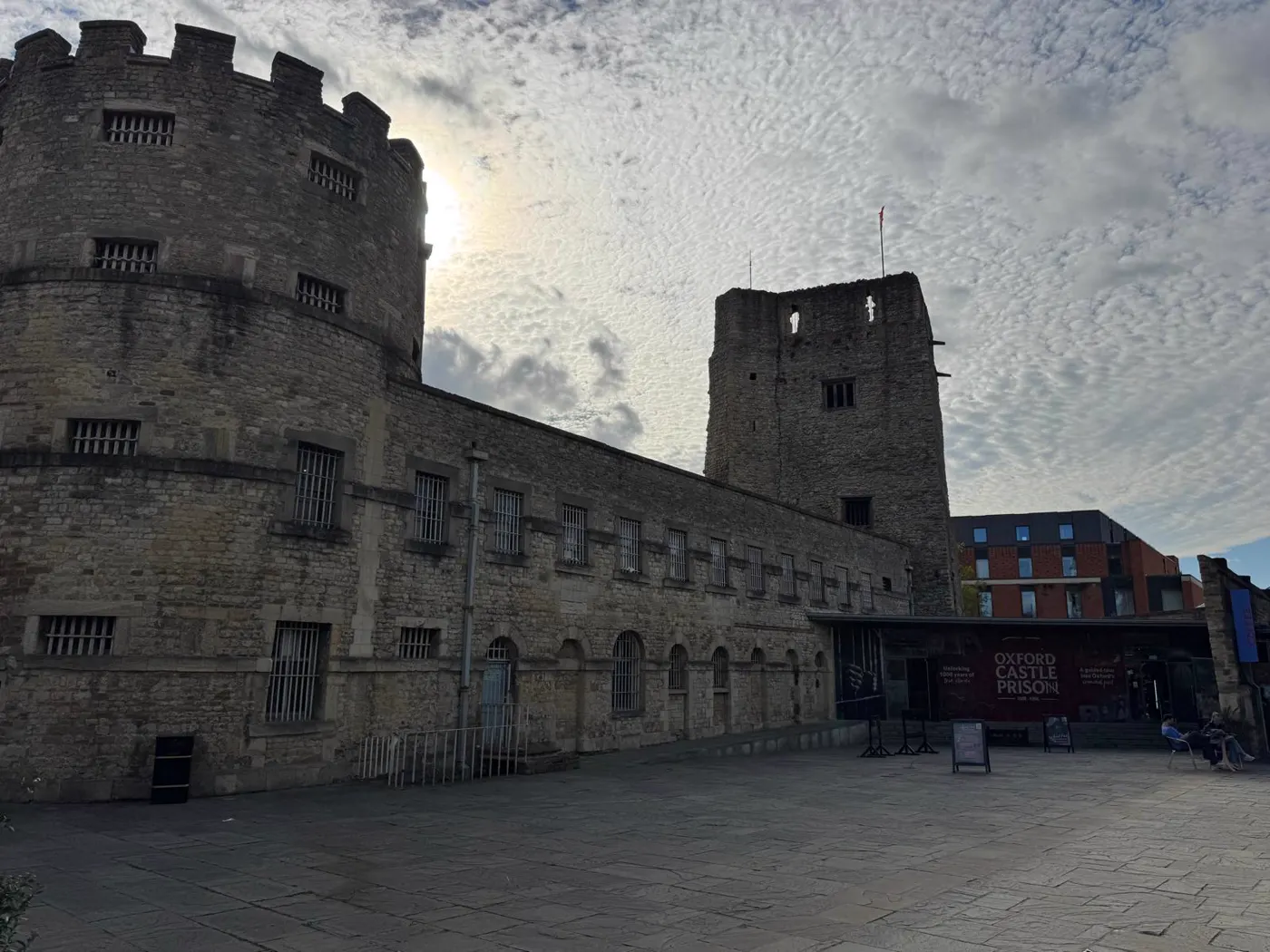 Oxford Castle and Prison from the courtyard, with the round tower, St George's Tower and the visitor entrance under a mackerel sky