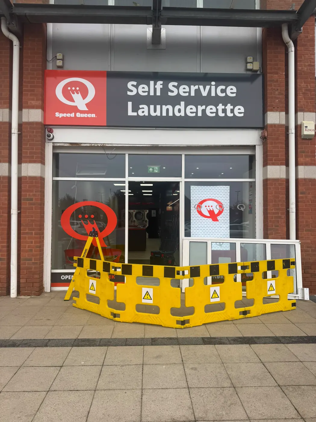 New Speed Queen self-service launderette in Thornaby with yellow barriers across the front entrance door and a stepladder in the doorway before opening