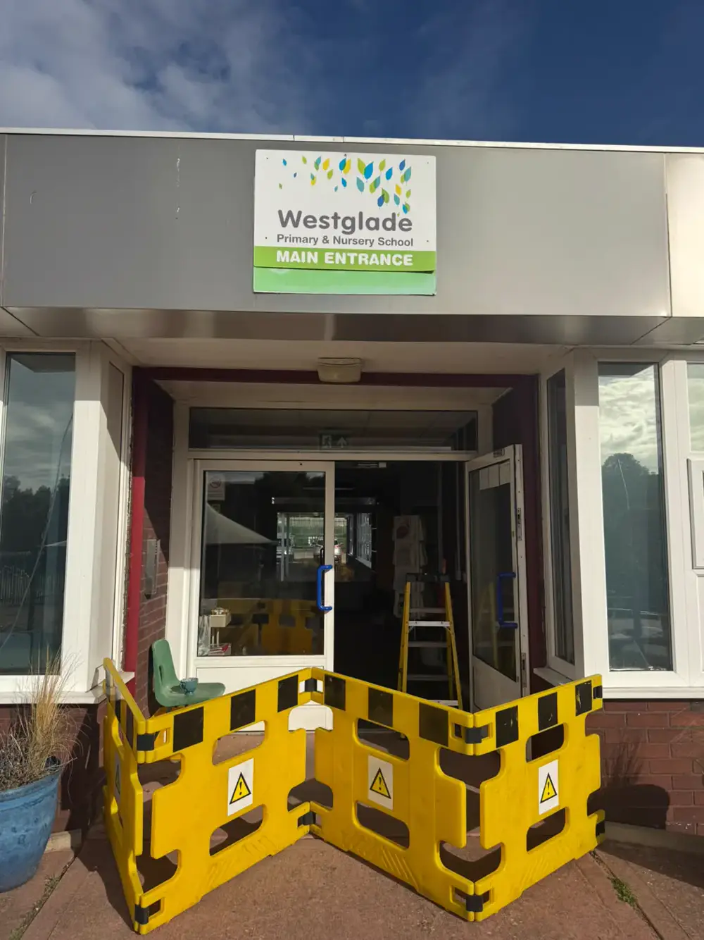Main entrance of Westglade Primary and Nursery School, Nottingham, cordoned with yellow barriers while the double aluminium door transom closers are replaced